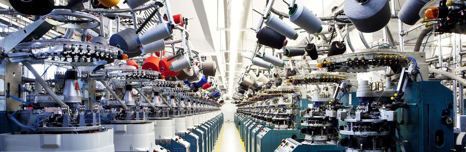 Rows of circular sock knitting machines with yarn cones overhead in the Sportingen mill
